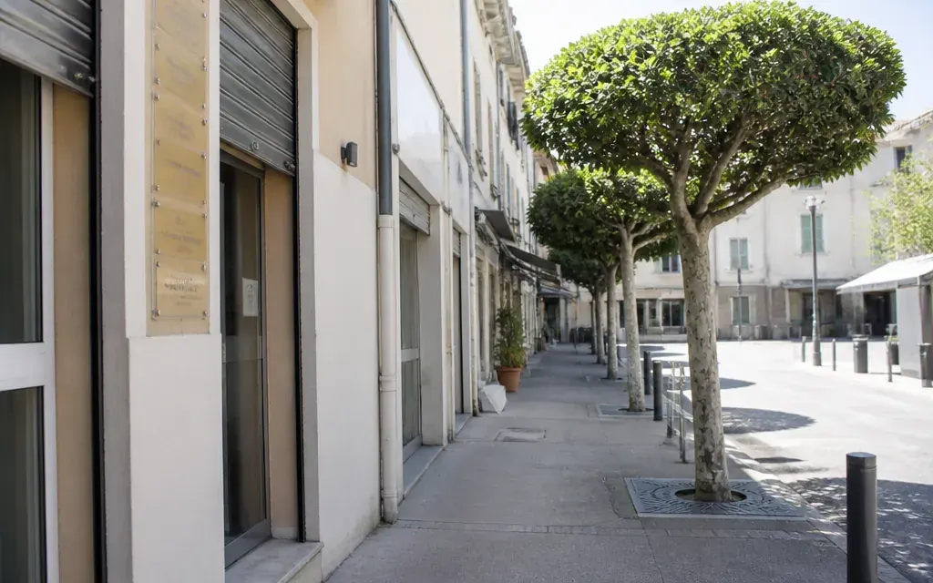 Rue commerçante de Carnoux-en-Provence en milieu de matinée, rideaux à demi levés, plaques de professions de santé…