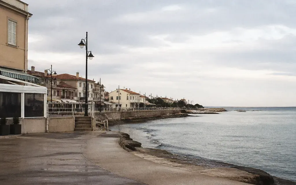 Front de mer de Sausset-les-Pins hors saison, terrasses repliées, un ou deux commerces ouverts, mer plate
